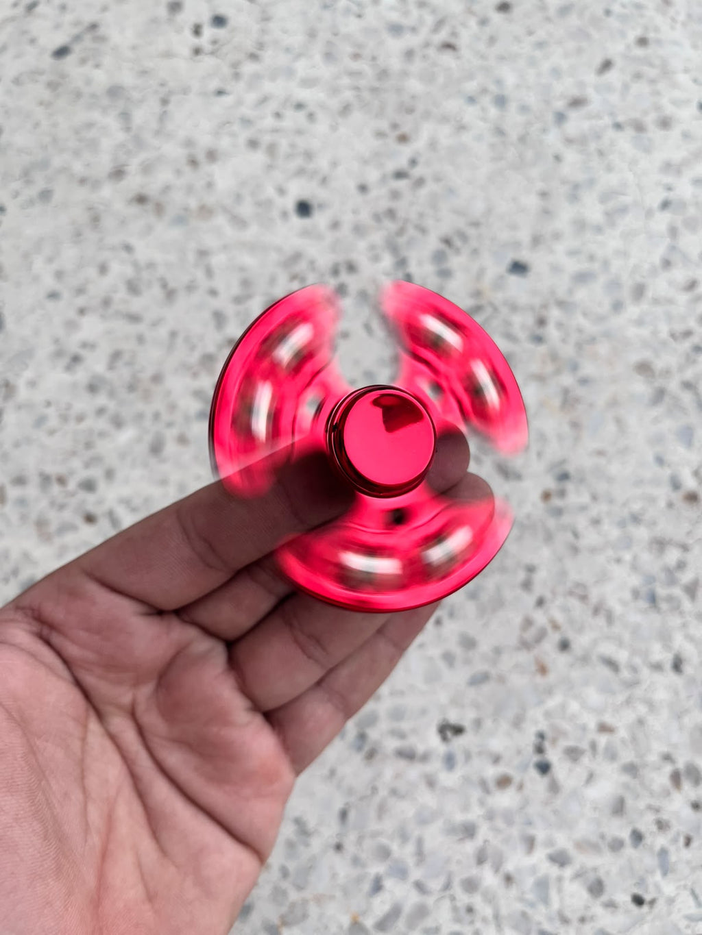 Red fidget spinner in a clear round case resting on an open palm