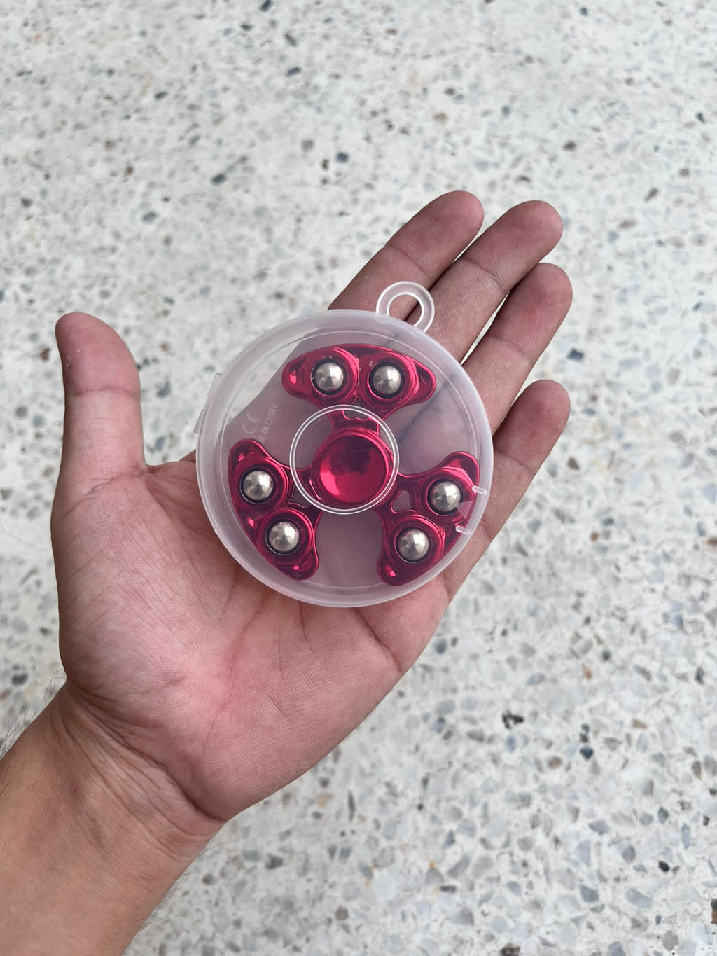 Close-up of a red three-arm fidget spinner in motion held in a hand