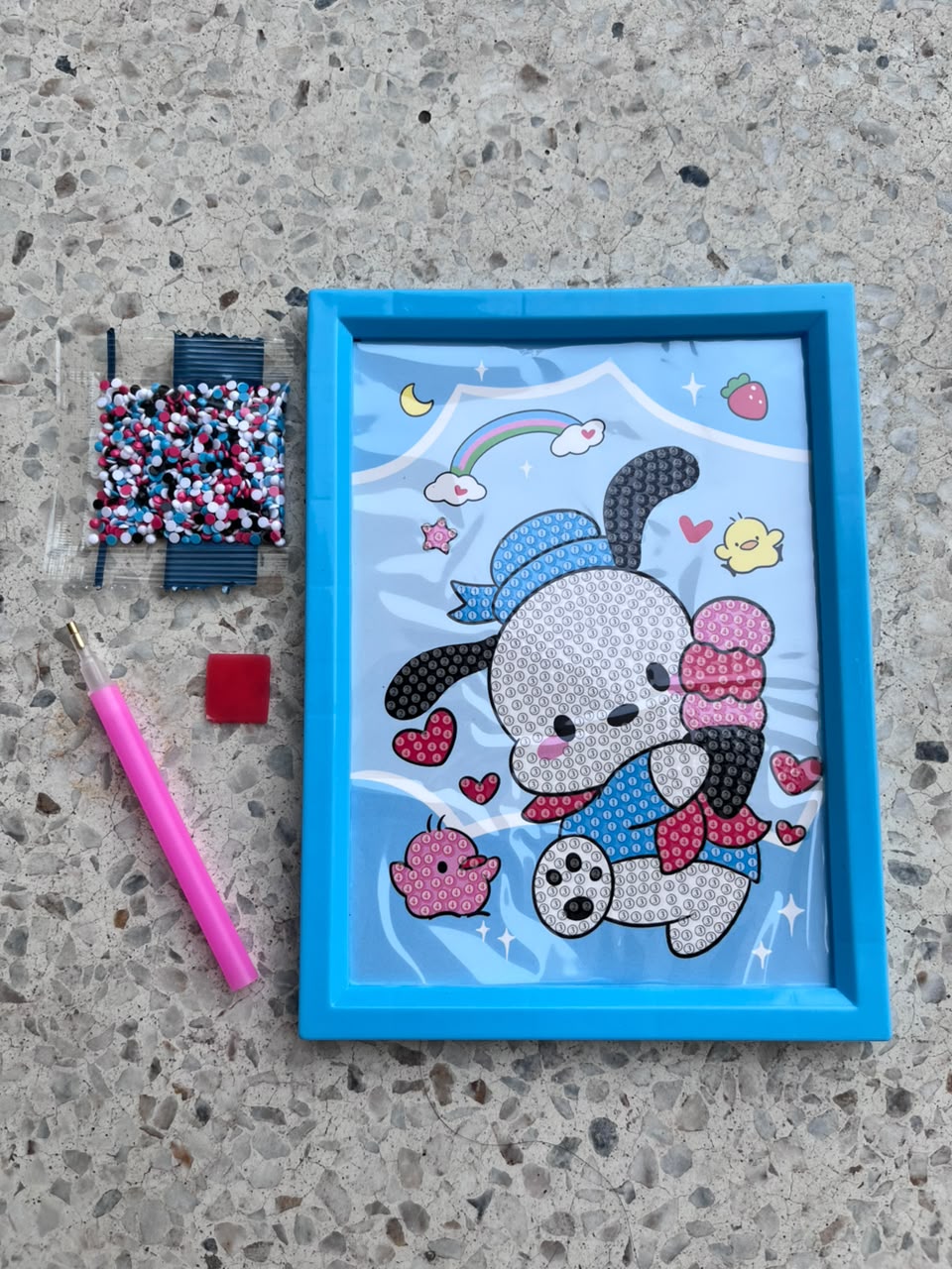 Blue-framed puppy diamond painting board held by its edge